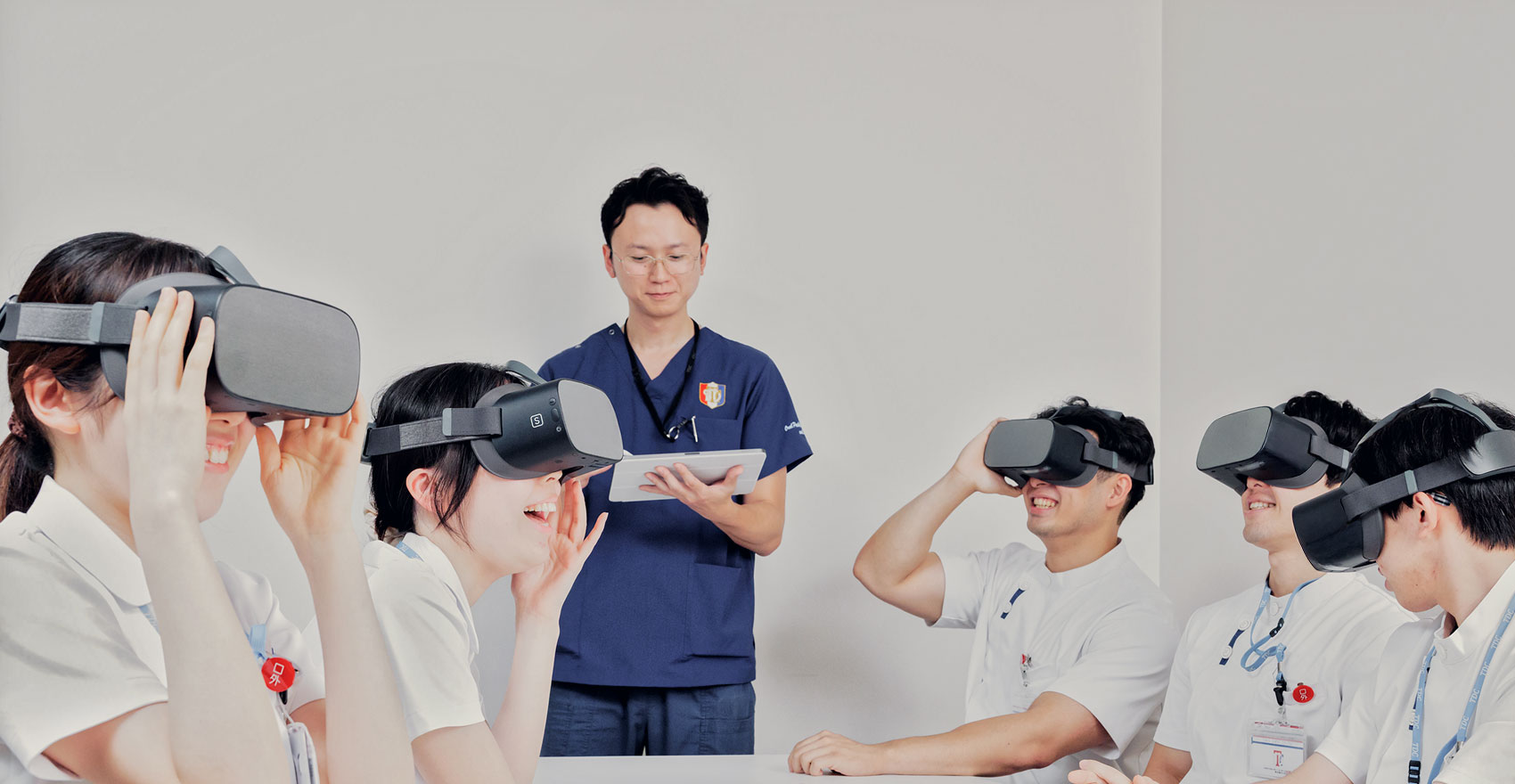 VRゴーグルをかけている学生と説明する教員